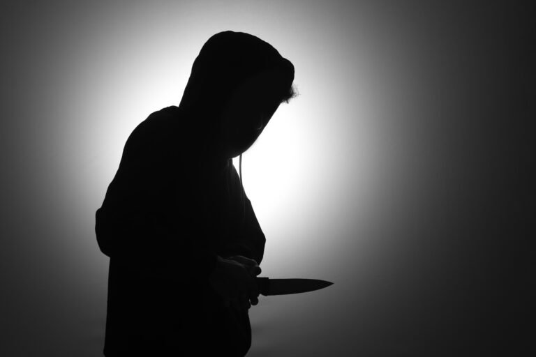 Mysterious man wearing black hoodie holding a knife to stab someone